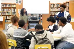  ?? STAFF PHOTO BY TIM BARBER ?? Brainerd High School junior Ashanti Bell, left, begins Tuesday’s Nooga Chat book club about the novel “The Hate U Give.” Ajayla Evan, standing right, and Ieesha Finch, seated second from right, listen to the opening statements.