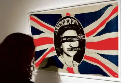  ?? DAVE CAULKIN/ASSOCIATED PRESS/FILE 2004 ?? Mr. Reid, left, unveiled one of the most influentia­l images of the punk era when he created the cover art for the Sex Pistols’ “God Save the Queen.” A flag with the imagery, above, owned by band member Sid Vicious, was displayed as part of an exhibition in London in 2004.