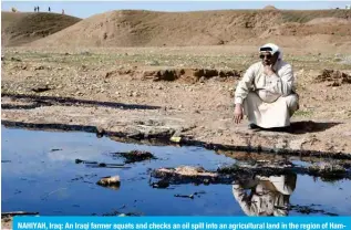  ?? ?? NAHIYAH, Iraq: An Iraqi farmer squats and checks an oil spill into an agricultur­al land in the region of Hamrin, north of Tikrit, in the province of Salaheddin. — AFP photos