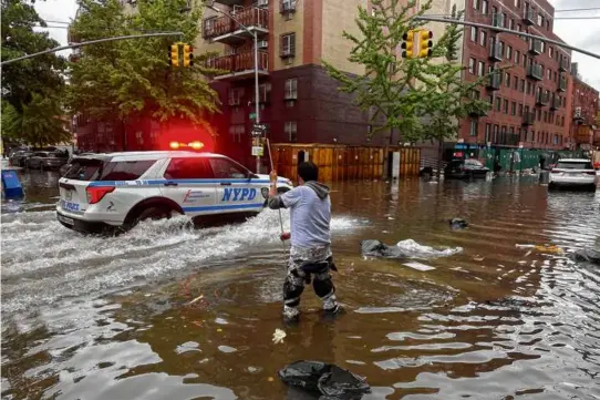  ?? JAKE OFFENHARTZ/ASSOCIATED PRESS ?? A man worked to clear a drain in flood waters, Friday, in the Brooklyn borough of New York.