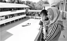  ?? Bernama photo ?? Flood victim Sarinah Amanah,32, cradles her son Aiman Nur Hakim Jamaludin, 4, while looking forlornly as the flood relief centre at Sekolah Kebangsaan Temai is affected by flood waters.-