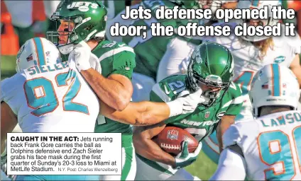  ?? N.Y. Post: Charles Wenzelberg ?? CAUGHT IN THE ACT: Jets running back Frank Gore carries the ball as Dolphins defensive end Zach Sieler grabs his face mask during the first quarter of Sunday’s 20-3 loss to Miami at MetLife Stadium.