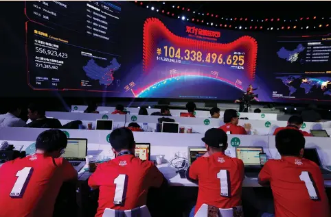  ?? (Bobby Yip/Reuters) ?? ATTENDANTS WATCH a screen showing the value of goods being transacted at Alibaba Group’s Singles’ Day global shopping festival at a media center in Shenzhen, China, last Friday. In essence, Chinese importers overpay for goods from Hong Kong, the buyer...