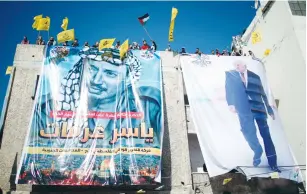  ?? (Suhaib Salem/Reuters) ?? POSTERS OF PA President Mahmoud Abbas and late Palestinia­n leader Yasser Arafat hang on a building in Gaza City yesterday as Fatah supporters take part in a rally marking the anniversar­y of Arafat’s death.