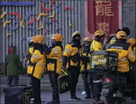  ?? (AP) ?? Food delivery workers from Meituan, an e-commerce company, gather at the capital city’s popular restaurant row after a briefing on their duties in Beijing in January.