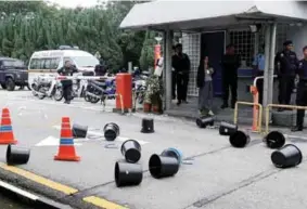  ??  ?? Plastic buckets and bottles seen strewn across the street at the main gate of the Selangor secretaria­t building in Shah Alam yesterday.