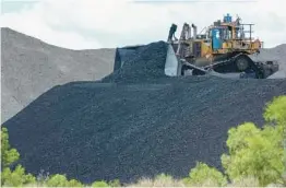  ?? MARK BAKER/AP 2021 ?? Coal is moved near Muswellbro­ok, Australia. In a first, the nation’s government recently rejected a coal mining applicatio­n based on environmen­tal law.