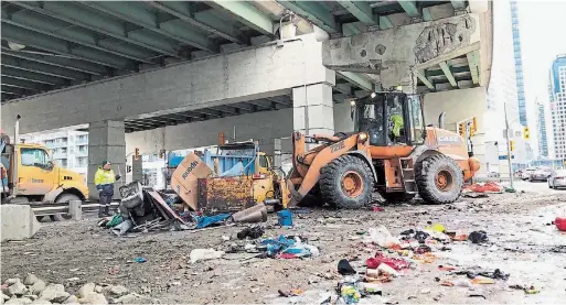  ?? RENÉ JOHNSTON TORONTO STAR ?? City workers tore down a makeshift encampment homeless people set up under the Gardiner Expressway Wednesday morning. They were finished by noon.