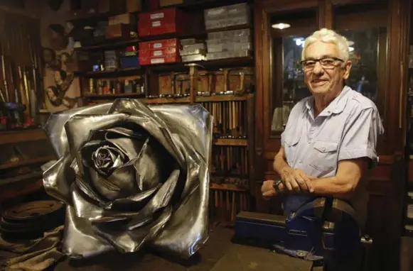  ?? VICTOR R. CAIVANO PHOTOS/THE ASSOCIATED PRESS ?? Juan Carlos Pallarols, 74, used pieces of war planes to make this large rose at his studio in Buenos Aires. Britain and Argentina fought a brief but bloody war in 1982.