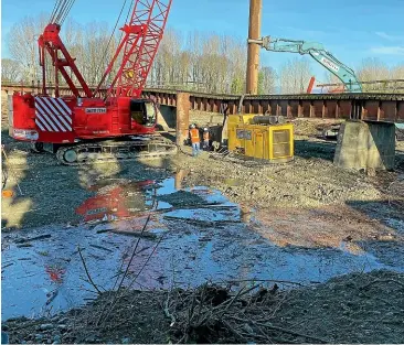  ??  ?? Repair work under way on a significan­t slump in the rail bridge over the Orari River. KiwiRail hopes the line will be open within a few days.