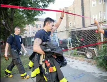  ??  ?? Chicago firefighte­rs walk under tape at the scene of a fire that killed several people including multiple children Sunday in Chicago. The cause of the blaze hasn’t been determined.