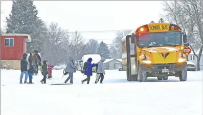  ?? Tom Stromme / The Bismarck Tribune photo via AP ?? Children in winter coats line up to get into a school bus on Thursday in Bismarck, N.D. Parts of Montana, the Dakotas, Minnesota, Illinois and Wisconsin are under winter weather advisories, with snow expected to start falling Thursday in some areas. Minnesota could see a foot of snow over the weekend, and parts of New England could also see 12 to 18 inches in the coming days.