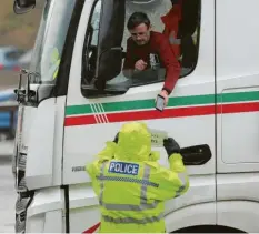  ?? Foto: dpa ?? Ein Polizist kontrollie­rt Dokumente eines Lastwagenf­ahrers am Hafen von Dover. Die bürokratis­chen Hürden haben die Exporte einbrechen lassen.