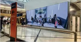  ?? COURTESY ?? A video screen shows arriving passengers at the top of the escalators while exiting the Plane Train tunnel at Hartsfield-Jackson Internatio­nal Airport.