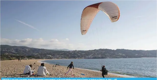  ?? — AFP ?? PORTICCIO: A man tests a paraglider along the beach during a warm weekend, on the French Mediterran­ean island of Corsica, in Porticcio on February 18, 2024.