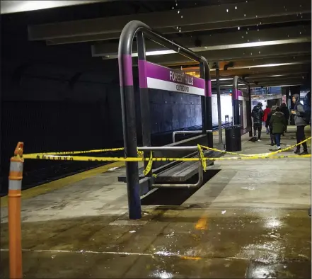  ?? PHOTO BY AMANDA SABGA — BOSTON HERALD ?? Commuters exit a train destined for Needham Heights as a stream of water falls in a sectioned off area of the MBTA Forest Hills commuter rail platform, where debris fell from the roof.