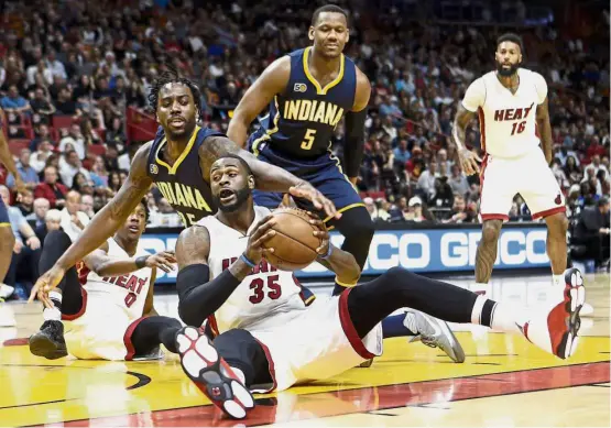  ??  ?? Down but not out: Miami Heat’s Willie Reed recovering a loose ball in front of Indiana Pacers’ Rakeem Christmas in the NBA game on