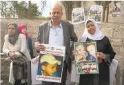  ?? MENAHEM KAHANA/AGENCE FRANCE-PRESSE VIA GETTY IMAGES ?? The father, Hussein, center, and mother, Suha, right of Palestinia­n teenager Mohammed Abu Khdeir, who was killed last year, stand with posters of their son outside the district court in Jerusalem on Monday.