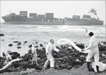  ?? Ritchie B. Tongo European Pressphoto Agency ?? A TEAM works last month to contain oil from a container ship that lost power in a storm and hit a reef after leaving port in Taiwan. About 200 government-organized workers gather daily to help with the cleanup.