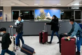  ?? Erin Schaff/The New York Times ?? Travelers wear face masks at Dulles Internatio­nal Airport in Dulles, Va., on March 12.