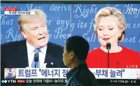  ?? (Kim Hong-Ji/Reuters) ?? A MAN WALKS past a TV screen broadcasti­ng the first presidenti­al debate between Hillary Clinton and Donald Trump yesterday in Seoul, South Korea.