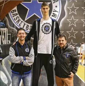  ?? ANDREW MEDICHINI / AP ?? Romanian teenager Robert Bobroczkyi, who stands 7-foot-7, towers over A.S. Stella Azzurra GM Giacomo Rossi (left) and club President Fabio de Mita.