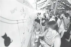  ??  ?? Festival goers doodling on the Doodle Wall at last year’s RWMF.