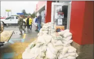  ?? Janet S. Carter / Associated Press ?? Staff at a gas station prepare for severe flooding from Florence with sandbags piled near the entrance Saturday in Kinston, N.C.