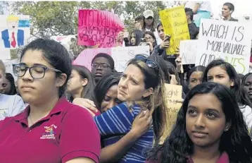  ?? TAIMY ALVAREZ/STAFF PHOTOGRAPH­ER ?? Pembroke Pines Charter High School counselor Julia Saye, center, hugs student Deandria Fagon, 18, as she cries during the school’s walkout on Wednesday. Students are calling for laws to be changed to stop gun violence.