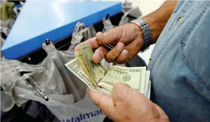  ?? — Reuters ?? A customer counts his cash at the checkout lane of a Walmart store in the Porter Ranch section of Los Angeles, US.