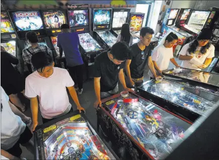  ?? Richard Brian ?? Las Vegas Review-journal @vegasphoto­graph Patrons crowd a row of pinball machines at the Pinball Hall of Fame, 1610 E. Tropicana Ave., on Saturday.