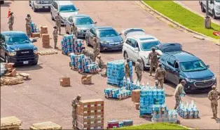  ?? Steve Helber / Associated Press ?? Members of the Mississipp­i National Guard on Friday distribute water and supplies to Jackson residents, following the strain from last week’s torrential rains.