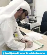  ??  ?? A Kuwait Municipali­ty worker fills a citation form during the campaign.