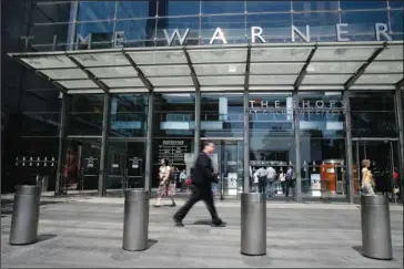  ?? The Associated Press ?? MEGADEAL: Pedestrian­s walk by an entrance to the Time Warner Center on May 26 in New York.