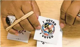  ?? BARBARA HADDOCK TAYLOR/BALTIMORE SUN ?? Election judge Deborah Claude-Jones holds stickers that she gives to voters at Randallsto­wn Community Center on Tuesday.