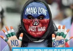  ?? —AFP ?? MUMBAI: An Indian student wearing a mask poses with her hands painted with a slogans for peace during a rally to mark Hiroshima Day.