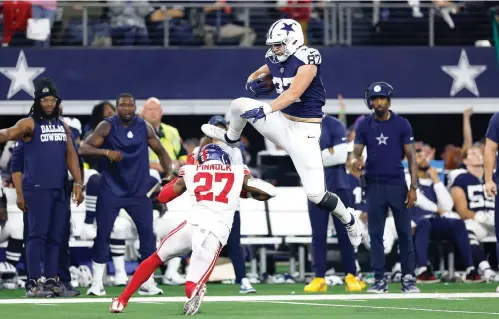  ?? (Wesley Hitt/getty Images/tns) ?? Jake Ferguson (87) of the Dallas Cowboys jumps over Jason Pinnock (27) of the New York Giants November 24 during the second half at AT&T Stadium in Arlington, Texas.