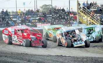  ?? BERND FRANKE/POSTMEDIA NEWS ?? Sportsman race cars go three wide rounding a corner at Merrittvil­le Speedway Saturday night in Thorold.