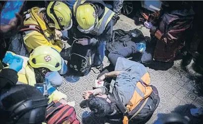  ?? XAVI JURIO ?? Un grupo de sanitarios atiende al periodista herido por el impacto de una botella en la calle Villarroel
