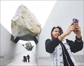 ?? Mel Melcon Los Angeles Times ?? MONICA CARTER OF CHICAGO takes a selfie in front of the “Levitated Mass” boulder sculpture at the Los Angeles County Museum of Art in Los Angeles, a favorite site among many visitors for self-portraits.