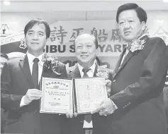  ??  ?? Sibu Resident Hii Chang Kee (left) during a photo call after presenting the presidenti­al instrument to Ngieng. Sibu Chinese Chamber of Commerce and Industry president Hu Yu Siong is at centre.