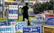  ?? JAY JANNER / AMERICAN-STATESMAN ?? A man walks past campaign signs outside a Travis County polling place in March. The county’s new voting system will have a paper audit trail for residents to check ballots.