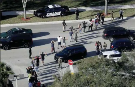  ?? MIKE STOCKER/SOUTH FLORIDA SUN-SENTINEL VIA AP ?? In this Feb. 14, 2018 file photo, students hold their hands in the air as they are evacuated by police from Marjory Stoneman Douglas High School in Parkland, Fla., after a shooter opened fire on the campus.