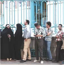  ??  ?? IRANIANS WAIT in a queue for the opening of the polling station to cast their ballots for the presidenti­al elections in Tehran on May 19.