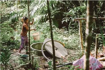  ??  ?? A villager in Kampung Pecah Bateri retrieving water from a water well. The water in the well is collected from rainwater and is contaminat­ed with insects, parasites, mould and bacteria.