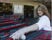  ??  ?? Belinda Padula smiles as she wipes down shopping carts with a disinfecta­nt wipe at Costco on Saturday in Chico.