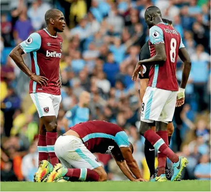  ?? PHOTO: REUTERS ?? West Ham’s Angelo Ogbonna and Cheikhou Kouyate look on as Winston Reid lies on the pitch after sustaining an injury.