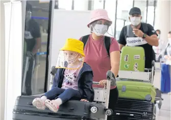  ?? PORNPROM SATRABHAYA ?? Passengers wear masks for protection as they arrive at Don Mueang airport.