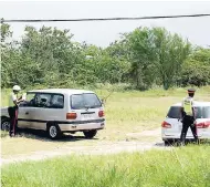  ?? IAN ALLEN/PHOTOGRAPH­ER ?? Traffic police dealing with motorists on a dirt track off Spanish Town Road in Kingston, where the cops issued tickets, warnings or just sent some motorists on their way outside of the glare of passers-by.