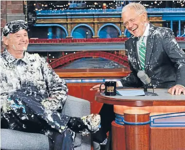  ??  ?? Guest Bill Murray celebrated David Letterman’s penultimat­e episode on late-night television by bursting out of a cake, covered in frosting and batter. Following a hug, the host and guest conducted their final segment together caked in the sugary mess,...